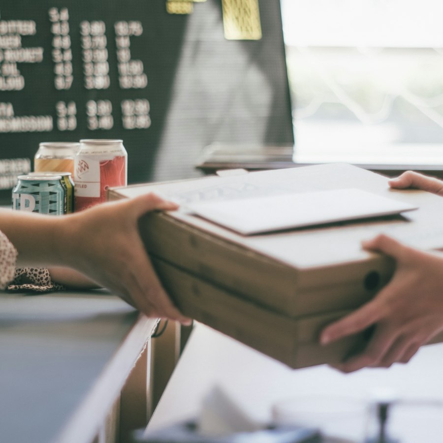 Hands passing a parcel across a sunny shop counter